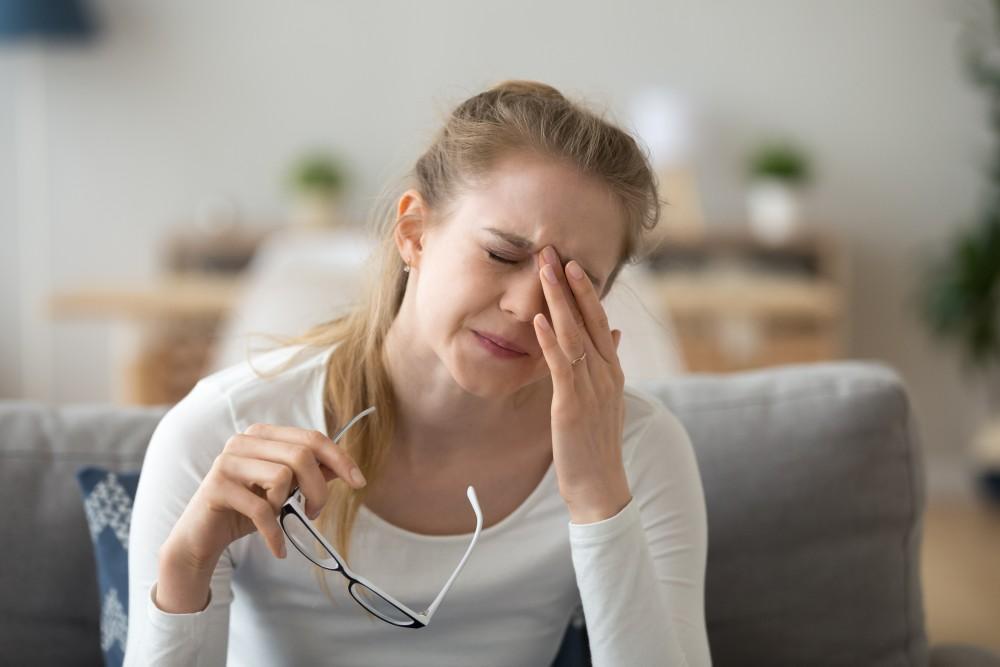 Woman rubbing eyes holding glasses