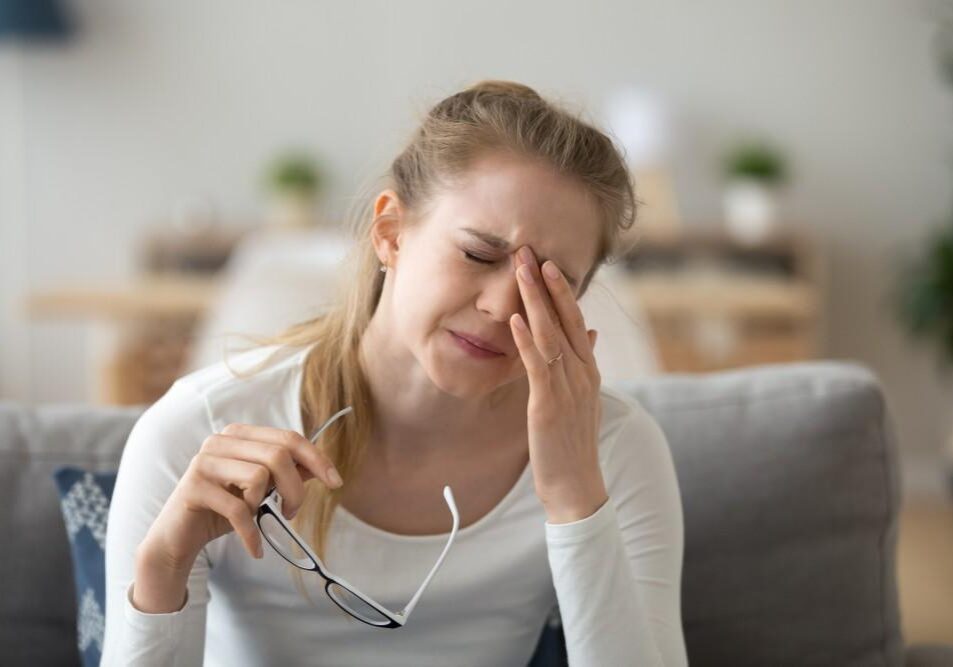 Woman rubbing eyes holding glasses